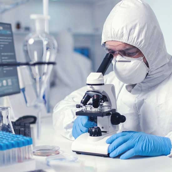 A microbiologist with protection glasses using microscope - Medical Equipment Supplier in UAE